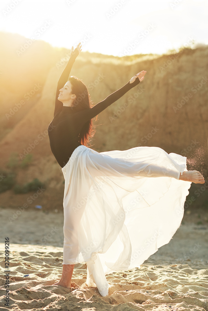 Naklejka premium Ballet woman Dancer at Sunset beach. Classical dance in white chiffon skirt