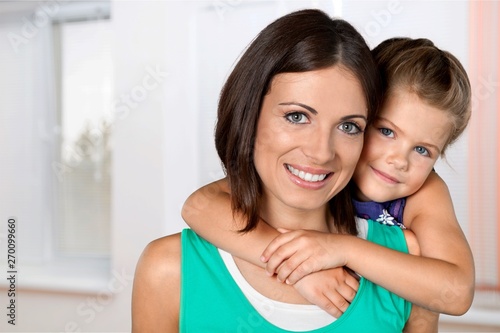 Mother and daughter hugging in bright bedroom