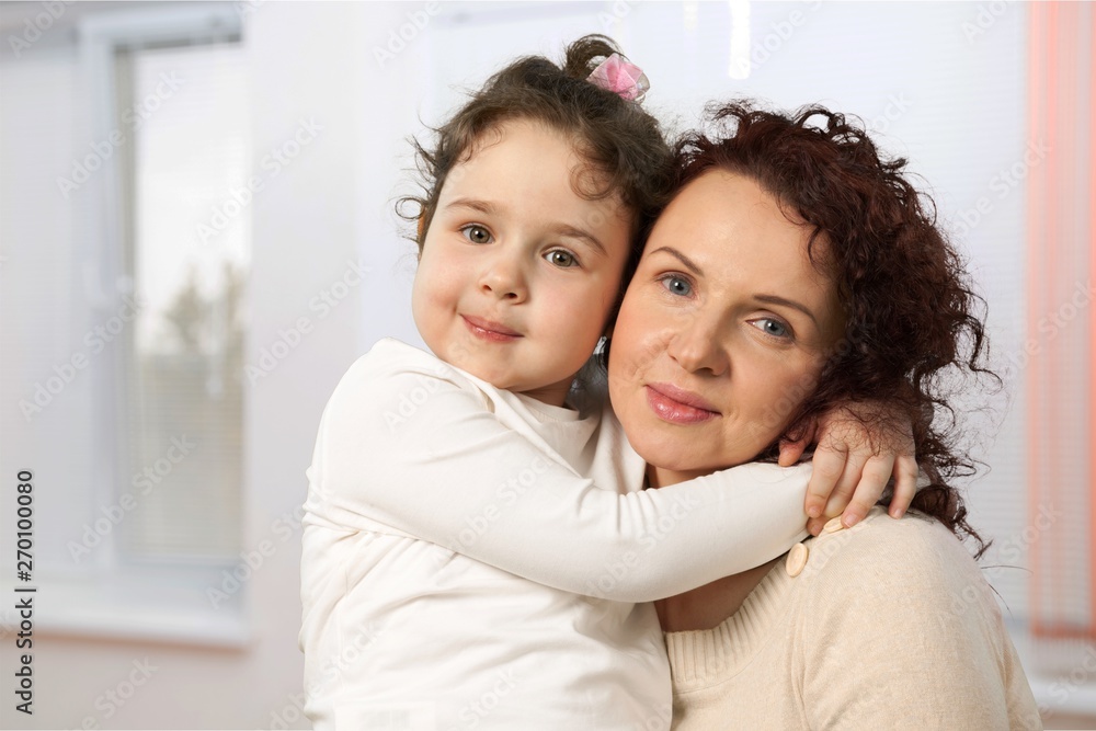 Mother and daughter hugging in bright bedroom Mother and daughter hugging in bright bedroom