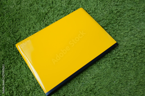 Yellow and black glossy laptop on a green carpet photo