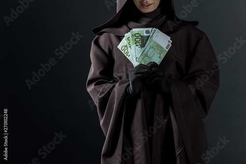 cropped view of woman in death costume holding euro banknotes isolated on black