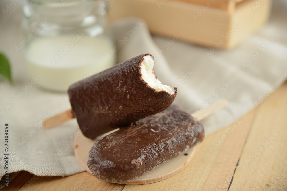 vanilla ice cream in chocolate coating, on a wooden table