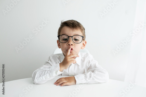 Cute little boy using laptop while doing homework against white background