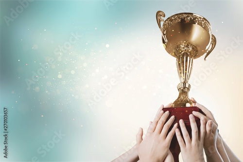 Hands holding golden trophy on a light background