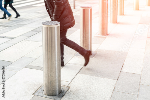 Man walking by stainless steel bollard entering pedestrian area on Vienna city street. Car and vehicle traffic access control