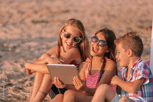 Photography Portrait of positive children laughing watching funny video on digital tablet on