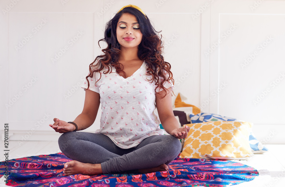 beautiful indian woman, doing yoga exercises at home, Padmasana or