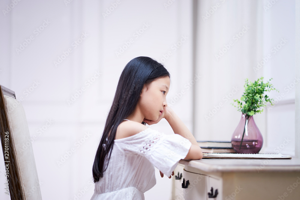 sad little asian girl sits at desk thinking sad little asian girl sits at desk thinking