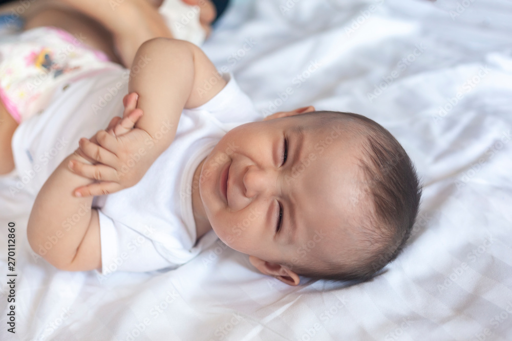 Angry 6 months old baby in bed. Little baby boy feeling uncomfortable and unhappy. Sad baby boy looking at camera. Copy space Angry 6 months old baby in bed. Little baby boy feeling uncomfortable and unhappy. Sad baby boy looking at camera. Copy space
