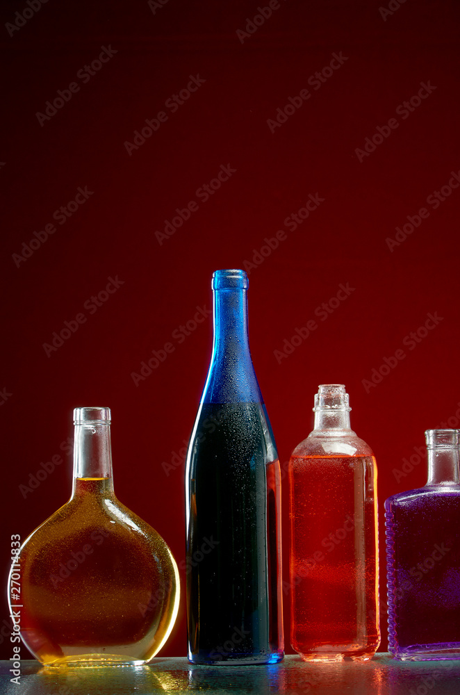 Different alcoholic drinks in transparent bottles on red background Different alcoholic drinks in transparent bottles on red background