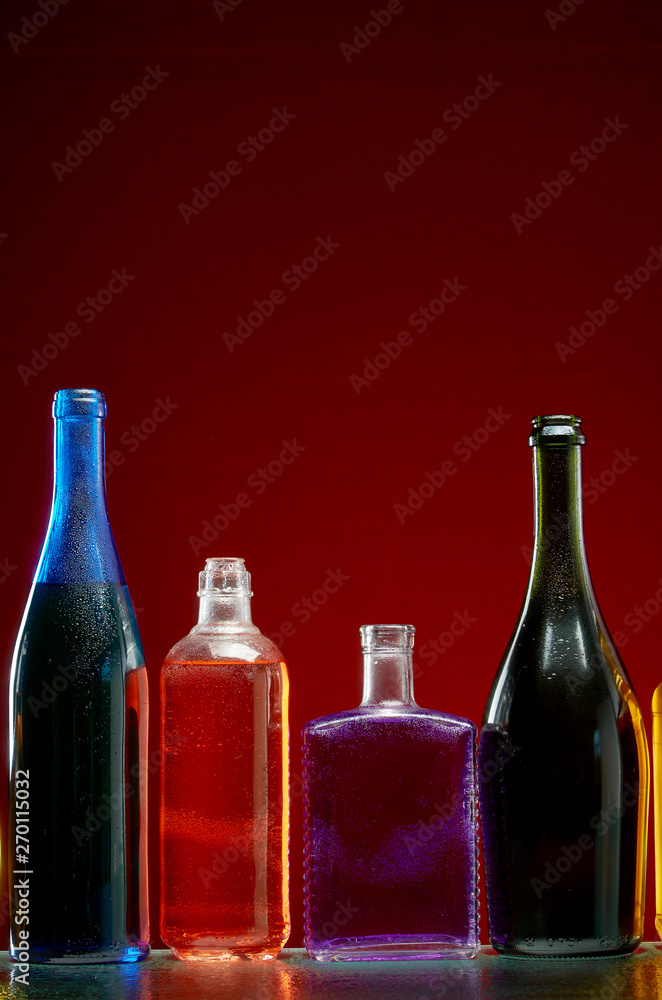 Different alcoholic drinks in transparent bottles on red background Different alcoholic drinks in transparent bottles on red background