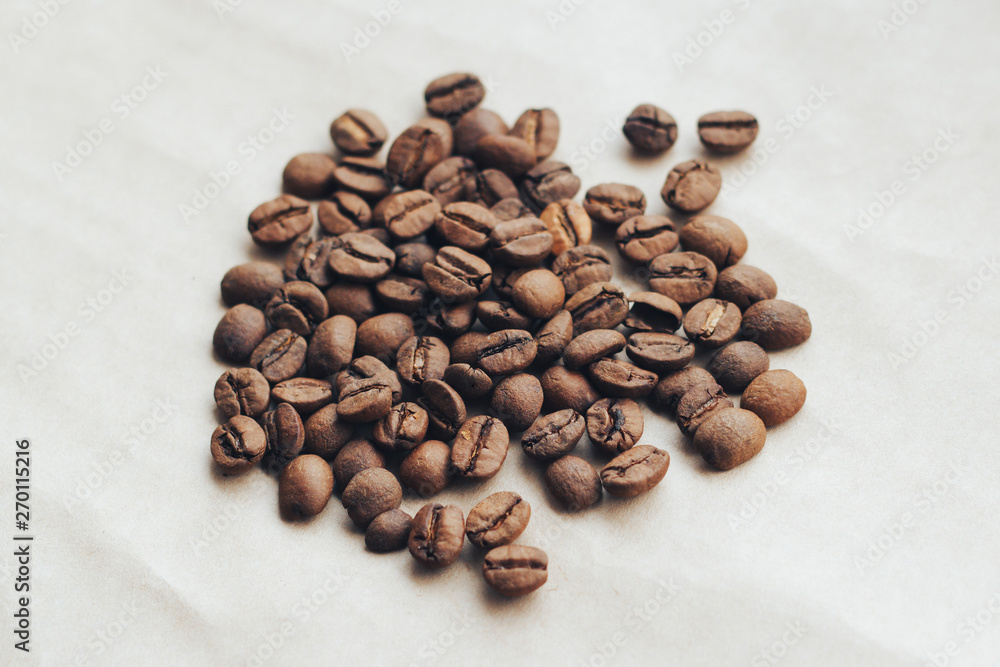 Fried coffee beans on paper background close up.