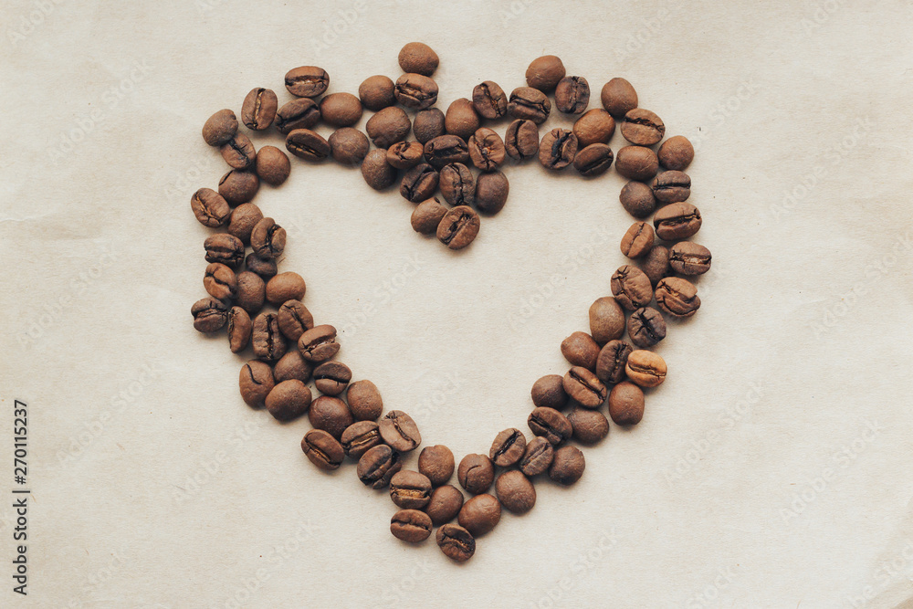 Fried coffee beans in the form of heart on a paper background. Fried coffee beans in the form of heart on a paper background.