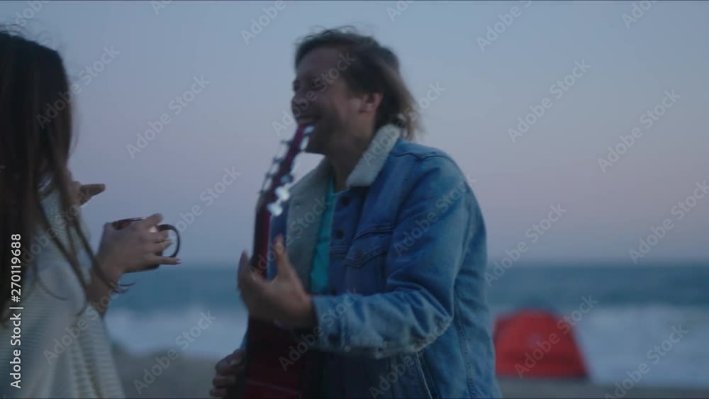 Lovely sunset at ocean coast. Playing guitar and dancing. Having fun together. Trip on trailer along coast of California. Lovely sunset at ocean coast. Playing guitar and dancing. Having fun together. Trip on trailer along coast of California.