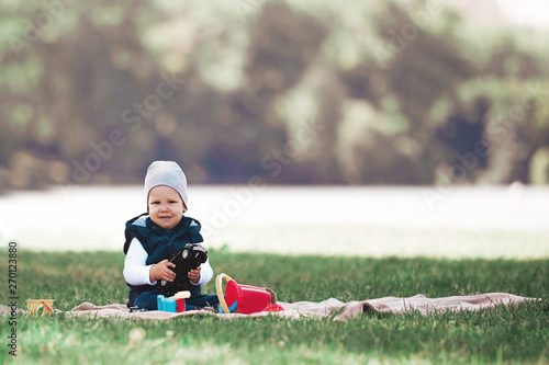 little boy playing with toys sitting on the lawn in the Park