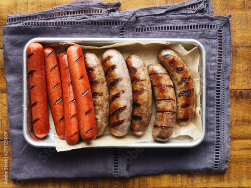 tray of grilled hot dogs and bratwursts on tray in top down composition photo