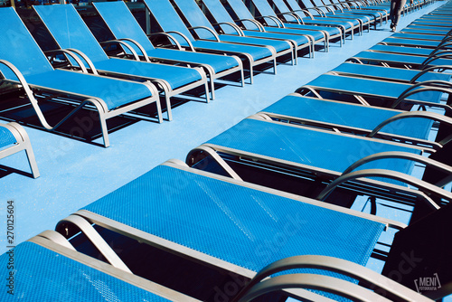 Blue lounge chairs on wooden floor on a Mediterranean sea cruise. © Alberto