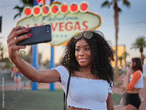 Photography african american woman taking selfie with smartphone in front of welcome to las