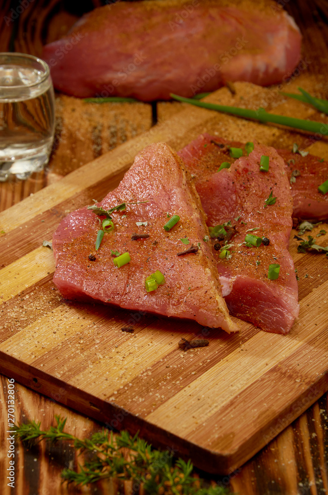 Fresh meat with herbs on a wooden Board cut into pieces and alcoho