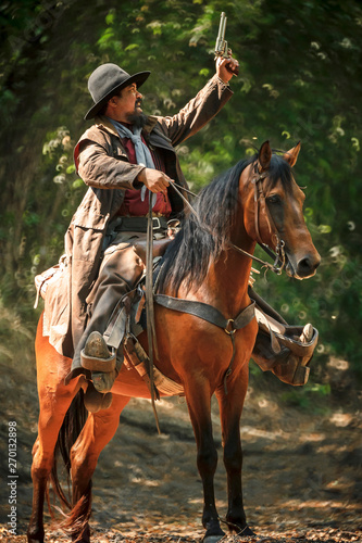 Cowboy riding a horse carrying a gun © weerachai