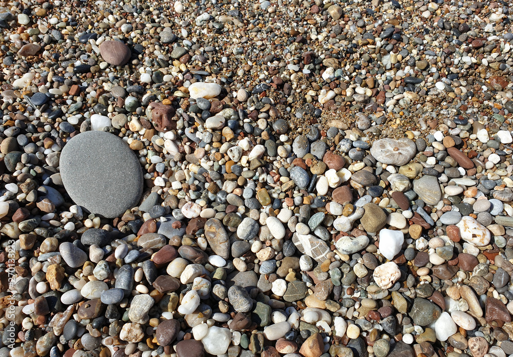 Multicolored large pebbles of various shapes on the sandy shore of the Mediterranean sea for backgrounds Multicolored large pebbles of various shapes on the sandy shore of the Mediterranean sea for backgrounds