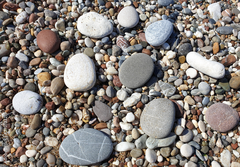 Multicolored large pebbles of various shapes on the sandy shore of the Mediterranean sea for backgrounds Multicolored large pebbles of various shapes on the sandy shore of the Mediterranean sea for backgrounds