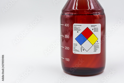 laboratory amber glass bottle with blank health hazard label on a field of white used in biology and medical research.. photo