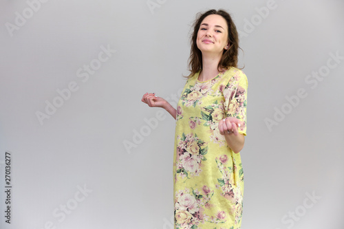 Life is a success. I am pleased with myself. Concept photo of a happy smiling woman satisfied life contented brunette girl in a yellow dress on a gray background with flowing hair.