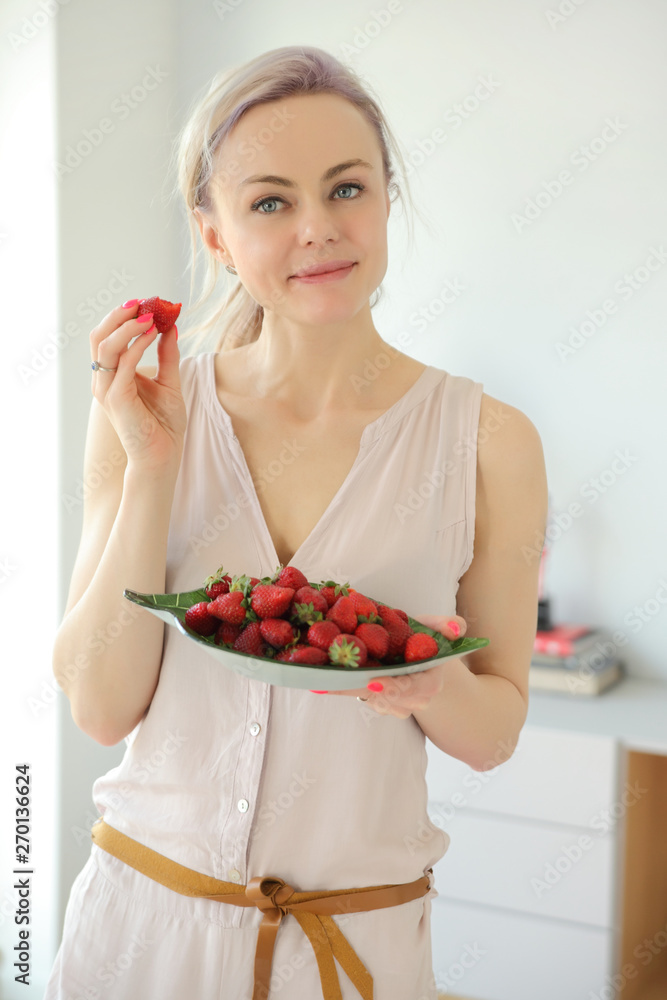 young positive smiling woman with a plate of strawberries young positive smiling woman with a plate of strawberries