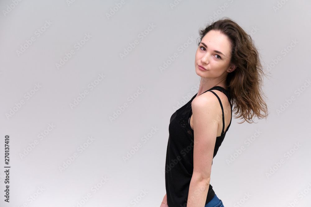 Life is a success. I am pleased with myself. Concept photo of a happy smiling woman satisfied life contented brunette girl in a black T-shirt and jeans on a gray background with flowing hair. Life is a success. I am pleased with myself. Concept photo of a happy smiling woman satisfied life contented brunette girl in a black T-shirt and jeans on a gray background with flowing hair.