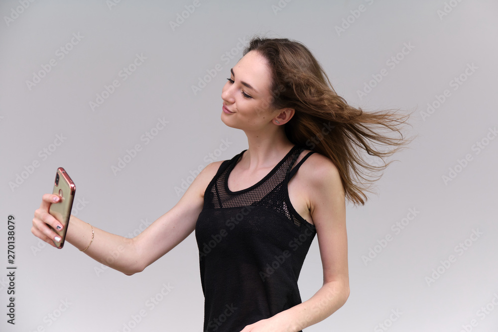 Life is a success. I am pleased with myself. Concept photo of a happy smiling woman satisfied life contented brunette girl in a black T-shirt and jeans on a gray background with flowing hair. Life is a success. I am pleased with myself. Concept photo of a happy smiling woman satisfied life contented brunette girl in a black T-shirt and jeans on a gray background with flowing hair.