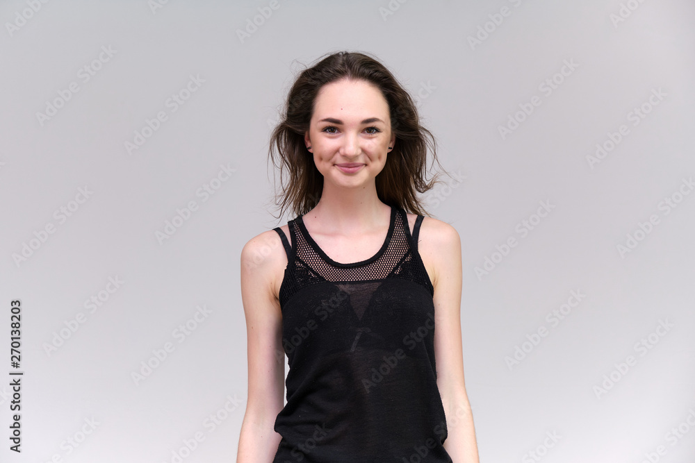 Life is a success. I am pleased with myself. Concept photo of a happy smiling woman satisfied life contented brunette girl in a black T-shirt and jeans on a gray background with flowing hair. Life is a success. I am pleased with myself. Concept photo of a happy smiling woman satisfied life contented brunette girl in a black T-shirt and jeans on a gray background with flowing hair.