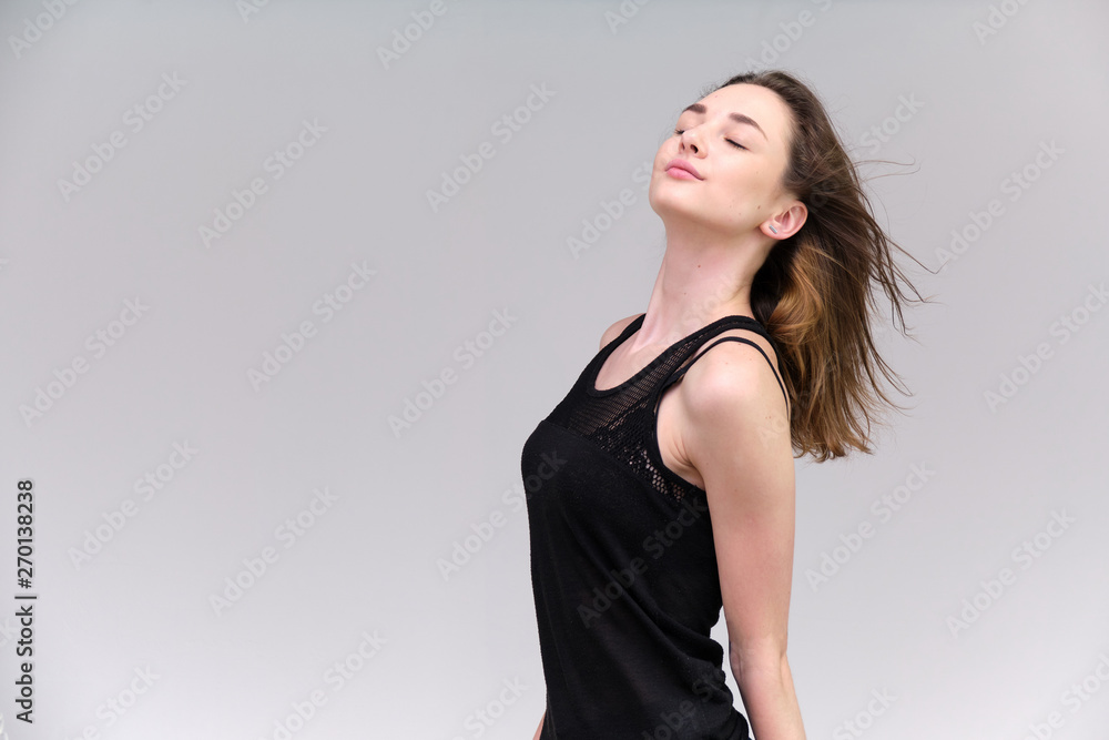 Life is a success. I am pleased with myself. Concept photo of a happy smiling woman satisfied life contented brunette girl in a black T-shirt and jeans on a gray background with flowing hair. Life is a success. I am pleased with myself. Concept photo of a happy smiling woman satisfied life contented brunette girl in a black T-shirt and jeans on a gray background with flowing hair.