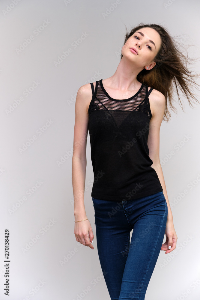 Life is a success. I am pleased with myself. Concept photo of a happy smiling woman satisfied life contented brunette girl in a black T-shirt and jeans on a gray background with flowing hair. Life is a success. I am pleased with myself. Concept photo of a happy smiling woman satisfied life contented brunette girl in a black T-shirt and jeans on a gray background with flowing hair.