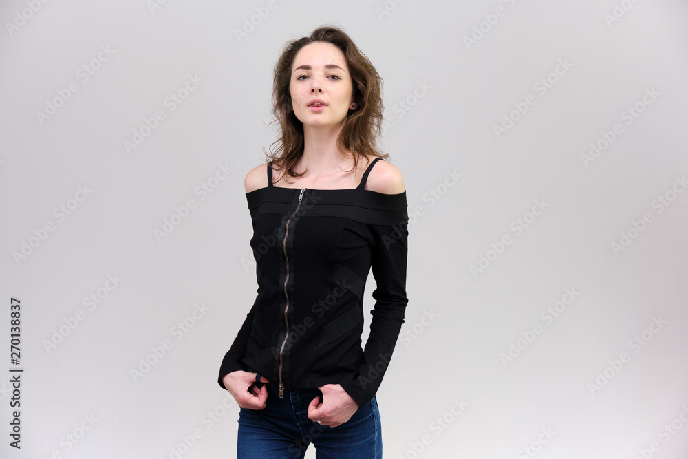 Life is a success. I am pleased with myself. Concept photo of a happy smiling woman satisfied life contented brunette girl in a black T-shirt and jeans on a gray background with flowing hair. Life is a success. I am pleased with myself. Concept photo of a happy smiling woman satisfied life contented brunette girl in a black T-shirt and jeans on a gray background with flowing hair.