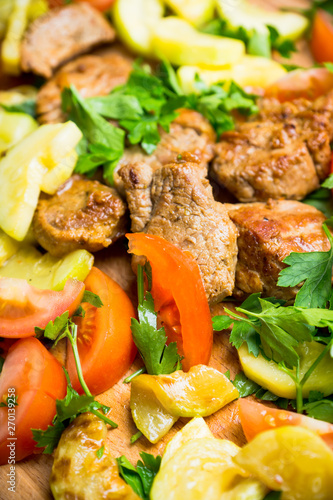 Grilled meat with vegetables on the wooden plate. Selective focus. Shallow depth of field.