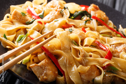 Slika na platnu Drunken noodles pad kee mao with chicken, basil, chili pepper and sauce close-up on a plate