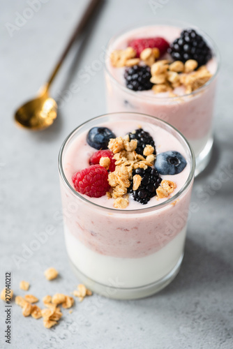 Healthy greek yogurt parfait with berries and granola in jar on concrete background. Concept of healthy eating, lifestyle. Vertical orientation