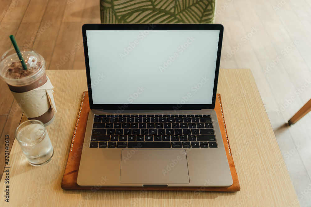 Fototapeta premium Laptop in the coffee cafe with white empty display.