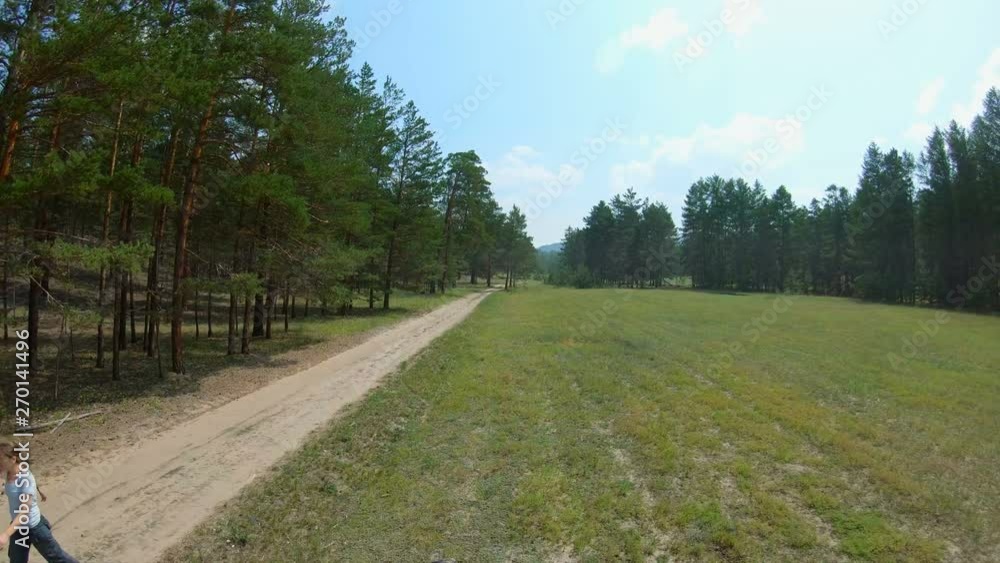 Girl walking on a country road. Aerial shot. Drone flies back past a woman. Slow motion