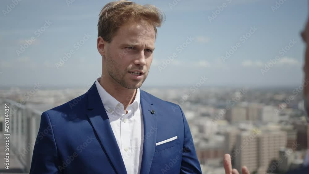Two businessmen discuss project's details on a rooftop. Process of making good business deal. Two businessmen discuss project's details on a rooftop. Process of making good business deal.