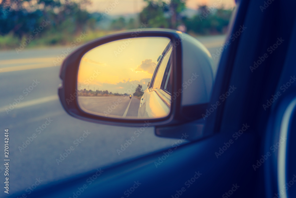mirror to see perspective road behind on sunset time.