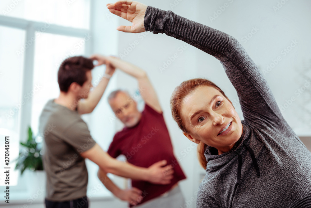 Obraz premium Joyful nice positive woman doing physical exercises