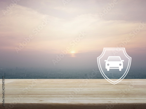 Car with shield flat icon on wooden table over aerial view of cityscape at sunset, vintage style, Business automobile insurance concept