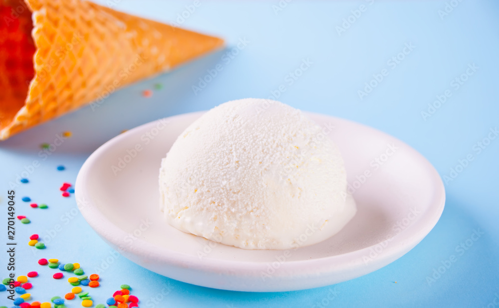 Vanilla ice cream with waffle cones and candy on the blue background Vanilla ice cream with waffle cones and candy on the blue background
