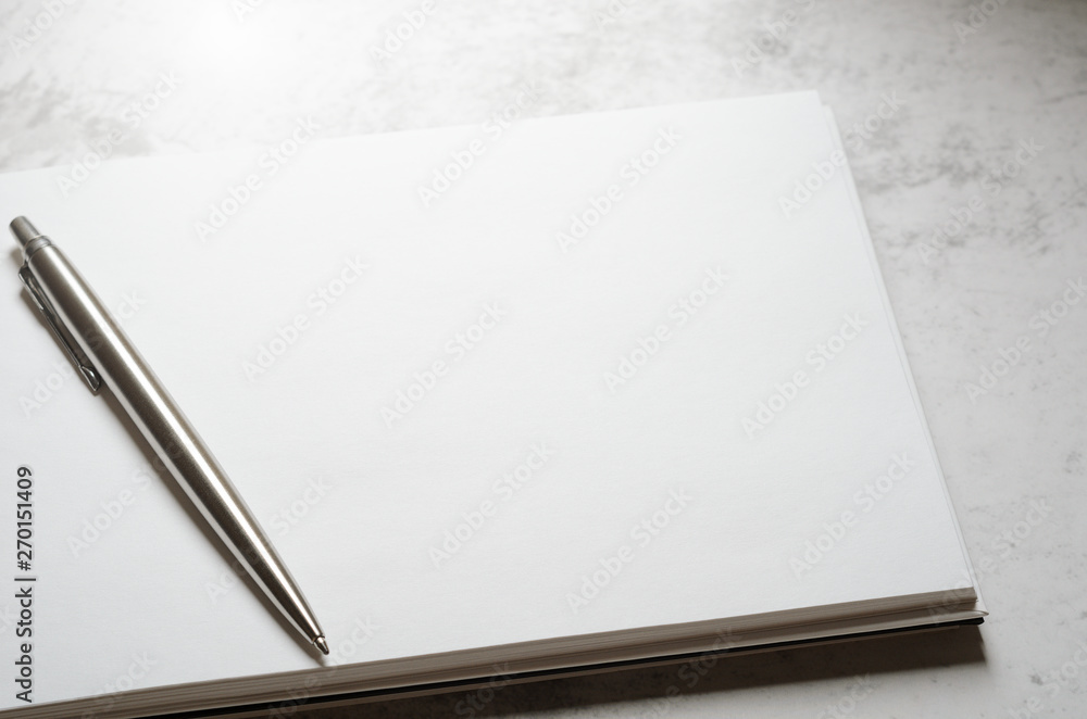 Naklejka premium Notepad with metal gray pen on a stone background. Concept elegant business style. Copy space