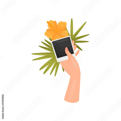 Hand is holding a leaf, a flower and a photo card. Poloroid. Vector illustration on white background.