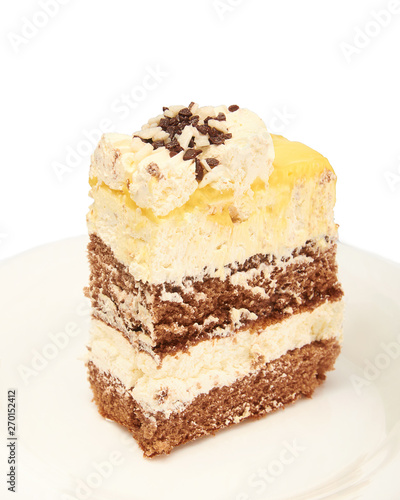 A piece of sweet fresh cake with yellow and chocolate cream on a plate on a white background