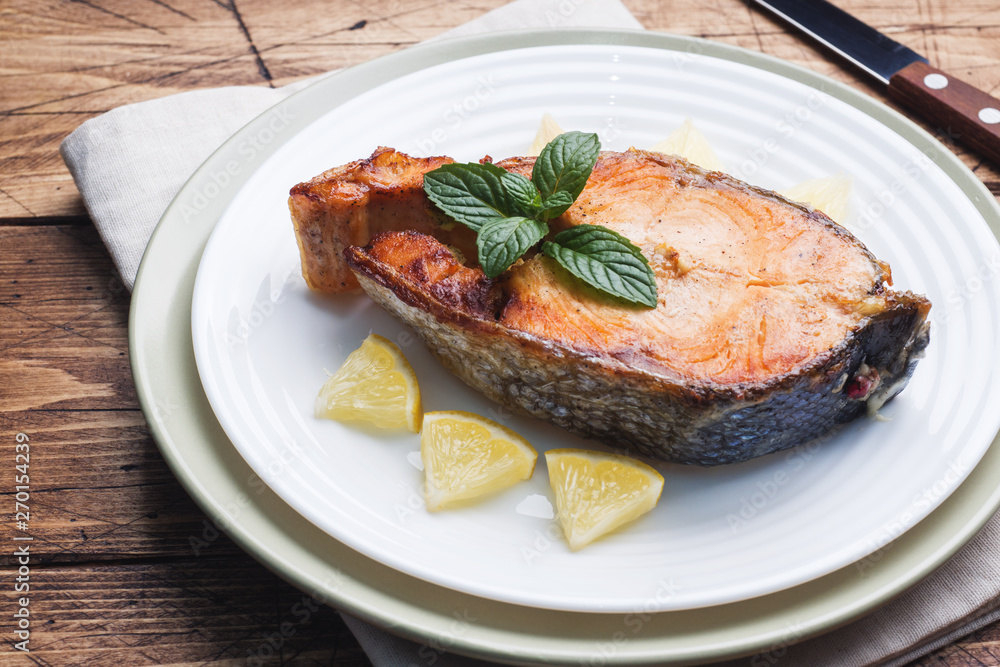 Steak baked fish salmon on a plate with lemon. Wooden table. Steak baked fish salmon on a plate with lemon. Wooden table.