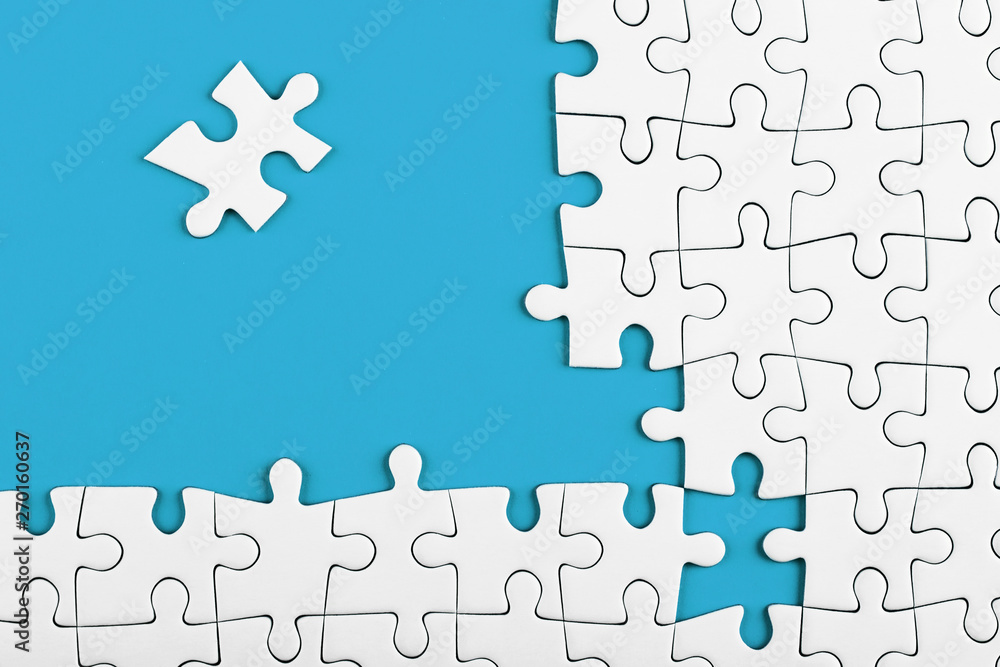 Fototapeta premium Unfinished white puzzle pieces on blue background